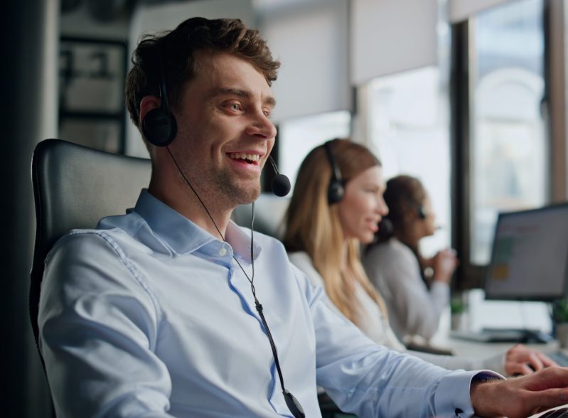 A friendly customer service interaction, with an agent smiling and talking with a customer. This illustrates the value of the 5 free ways to improve customer experience in 2025.