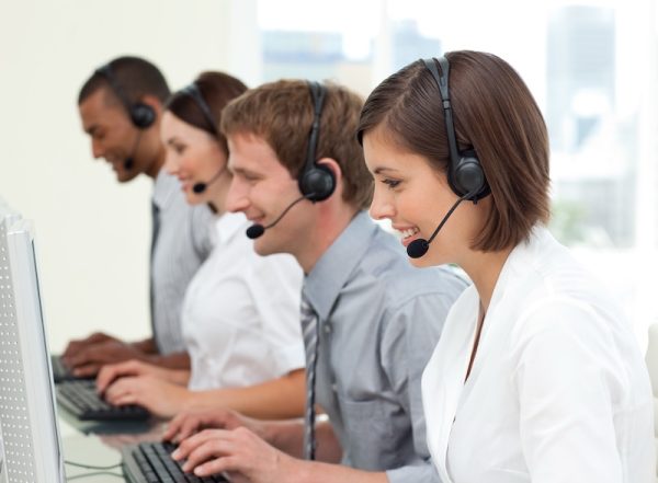 A friendly customer service team working on computers in a modern contact center, using a cloud contact center solution